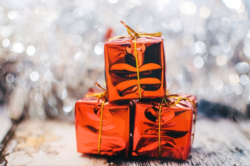 Image-of-three-small-presents-wrapped-in-shiny-red-paper-on-silver-background